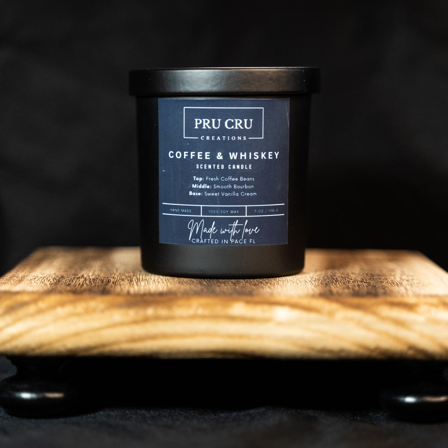 Pru Cru Coffee & Whiskey candle on a wooden stand with a dark background