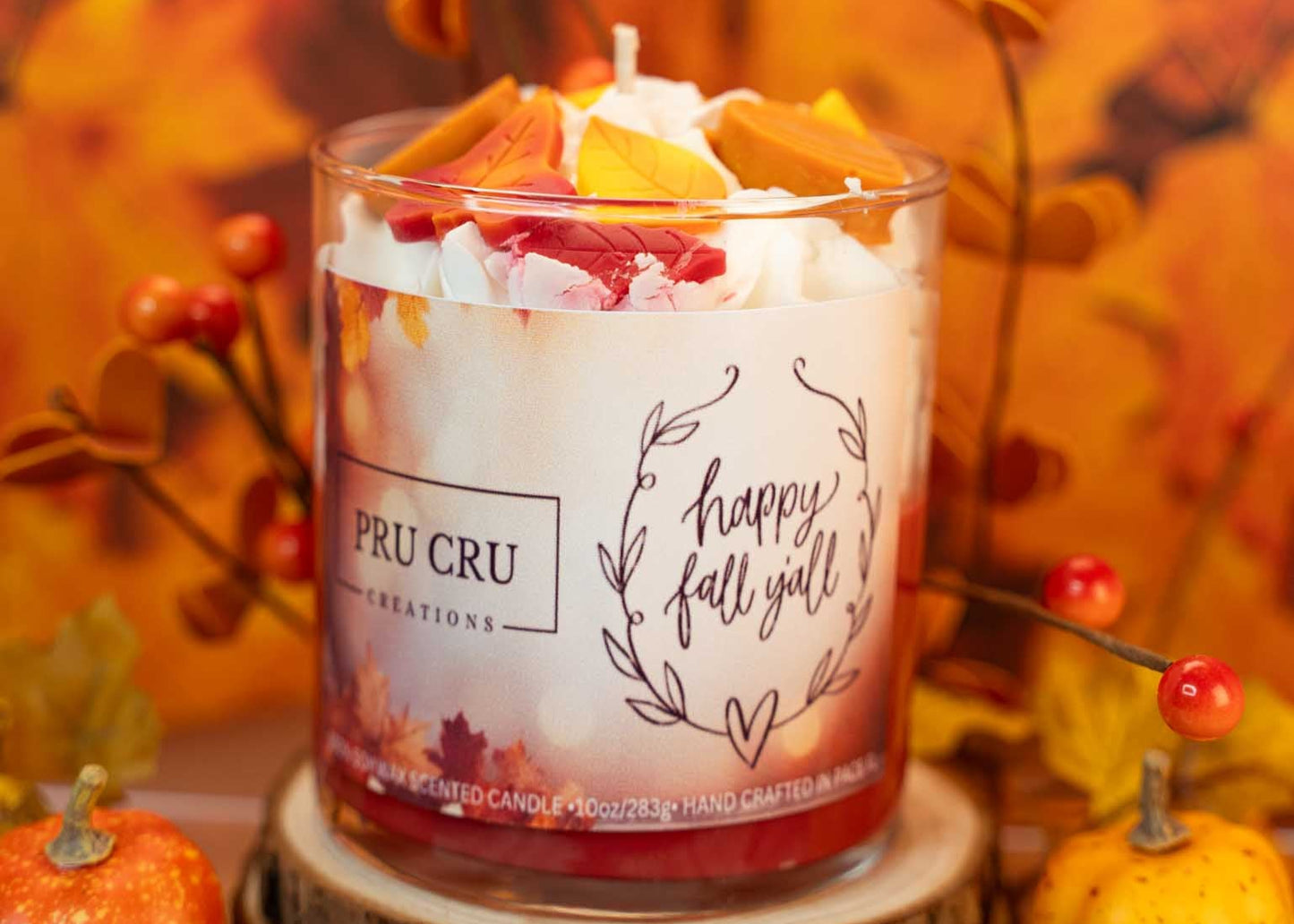 Candle labeled 'Happy Fall Y'all' with autumn-themed decorations in the background