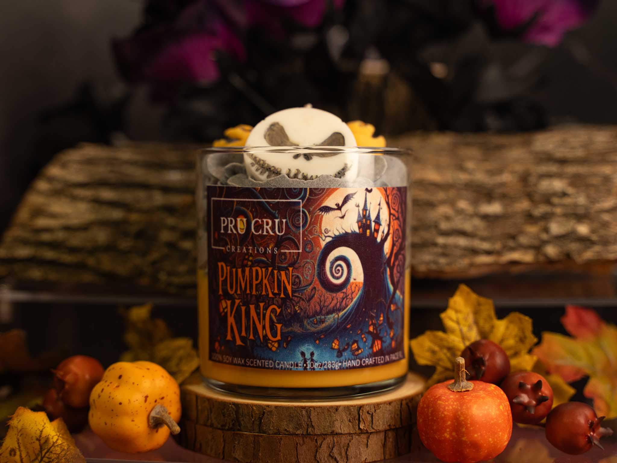 Pumpkin King candle with decorative skull on top, surrounded by autumn decorations.
