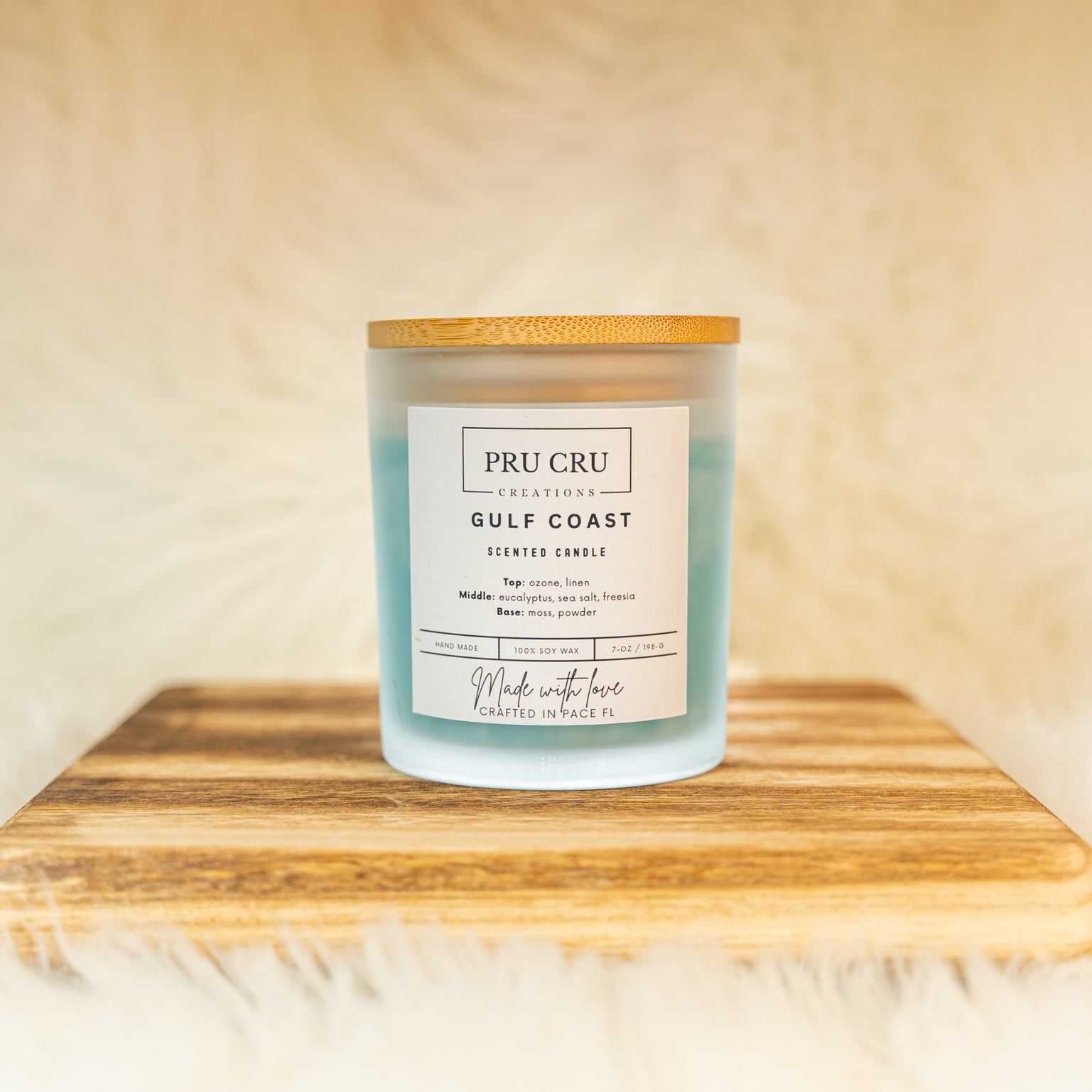 Pru Cru Gulf Coast scented candle on a wooden board with a soft beige background