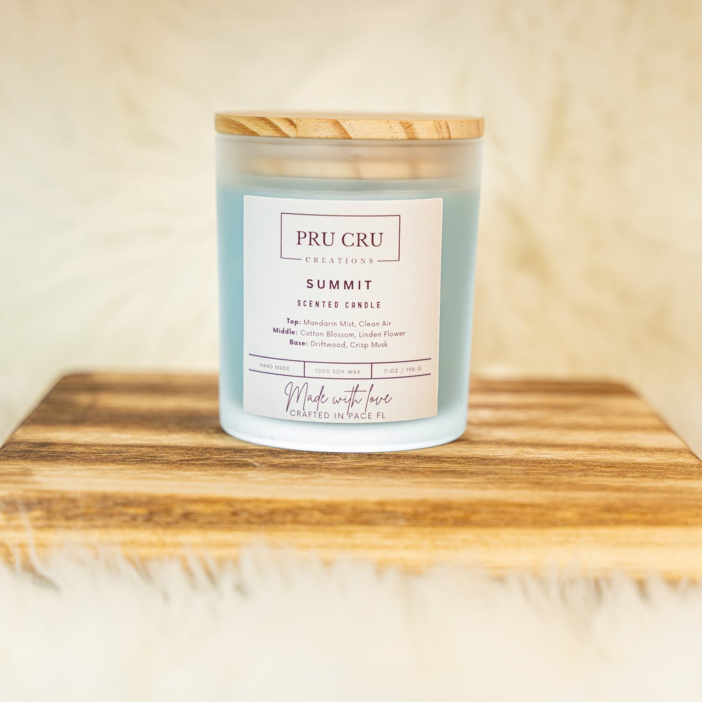 Pru Cru Summit scented candle on a wooden surface with a soft background