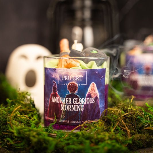 Candle with 'Pru Cru' packaging on a bed of moss, surrounded by similar candles.