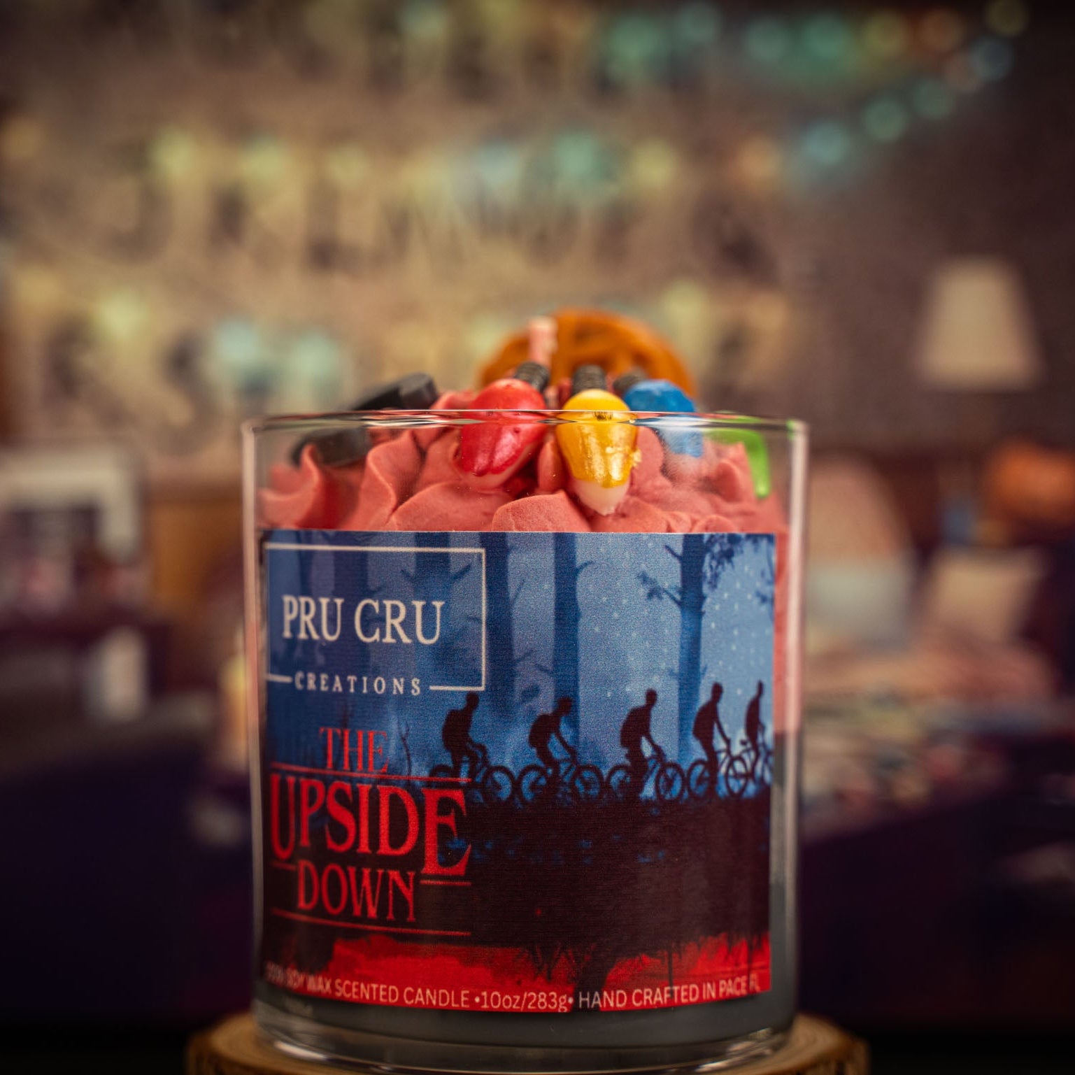 Pru Cru candle labeled 'The Upside Down' with colorful wafers on a blurred background